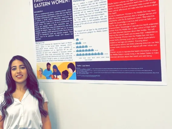 Layal- Standing in front of her academic poster. 