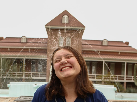 Student Bree Lynn, smiling in front of the fountain at Old Main 