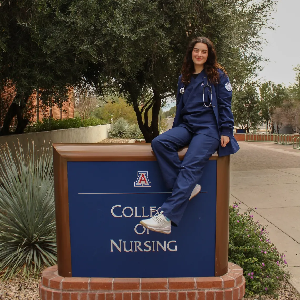 Photos Melissa Hailey sitting on a College of Nursing sign