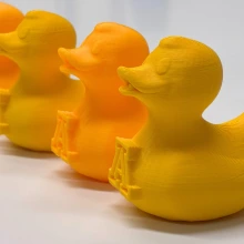 A row of yellow 3D printed ducks on a white tabletop